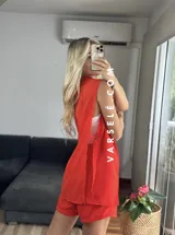 Conjunto color naranja compuesto por un chaleco sin mangas con solapas y un short de tiro alto con elástico en la parte trasera.