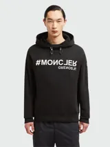 Sudadera con capucha Moncler Grenoble negra con estampado frontal de hashtag y texto invertido.