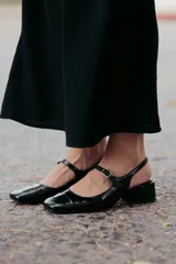 Zapato estilo Mary Jane con diseño destalonado, confeccionado en cuero color beige. Presenta una tira fina con hebilla metálica sobre el empeine, punta redondeada y taco cuadrado forrado de 6 cm de altura.