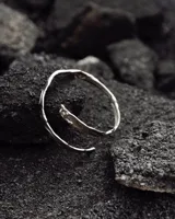 Brazalete rígido de diseño minimalista con forma de espiral, elaborado artesanalmente en bronce y alpaca maciza. Es una pieza ajustable que puede lucirse tanto en el antebrazo como en la parte superior del brazo.