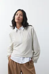 Sweater de tejido de punto color beige con sutil hilo metalizado, cuello redondo y mangas largas amplias con diseño holgado.