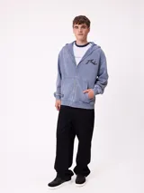 Canguro con capucha de color negro con efecto lavado, manga larga y bolsillo frontal. Presenta un estampado gráfico en la espalda con el logo de la marca y motivos abstractos en tonos violeta y amarillo.