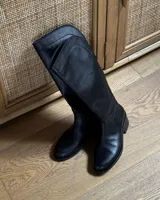 Bota alta de cuero vacuno color negro, con caña alta y taco bajo.