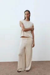 Top de punto color crema, de cuello redondo y sin mangas.