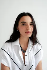 Vestido camisero corto blanco de algodón con bordados negros, cuello camisero, cierre frontal con botones y sin mangas.