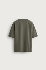Camiseta boxy fit color verde militar con efecto lavado, confeccionada en tejido compacto de algodón, con cuello redondo y manga corta.