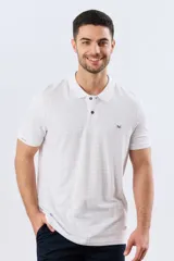 Remera polo de piqué manga corta, color blanco con estampado geométrico sutil. Presenta cuello camisero y cartera con dos botones oscuros.