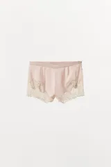 Shorts de tiro medio confeccionado en satén, con detalle de encaje y bordados florales a contraste en el ruedo. Presenta cierre lateral con botones.