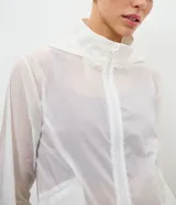 Campera cortavientos deportiva modelo cropped, color blanco traslúcido, con cierre frontal de cremallera, capucha estructurada, puños elásticos y bajo ajustable con cordón.