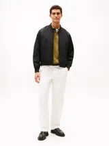Campera bomber Tommy Hilfiger de color negro, confeccionada con tejido técnico de nailon reciclado y poliamida resistente al viento y la humedad ligera. Presenta diseño de corte clásico con cierre frontal de cremallera, cuello, puños y dobladillo en rib elástico, y dos bolsillos laterales de ojal. Incluye el logo monotipo bordado discretamente en el pecho.
