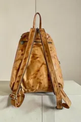 Mochila de cuero terracota con diseño artístico pintado a mano en el bolsillo frontal, múltiples compartimentos con cierre y herrajes metálicos en tono oro viejo.