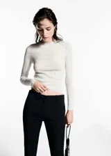 Jersey de punto canalé en color blanco, con diseño entallado, cuello perkins, manga larga y detalle de strass aplicado en toda la prenda.