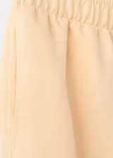 Pantalón de lino color beige, de diseño recto y largo con tiro medio, dos bolsillos laterales y cintura ajustable.