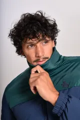 Campera puffer con diseño bicolor, cuerpo en azul marino y canesú superior en verde oscuro. Presenta cuello alto, cierre frontal completo y puños elásticos.
