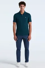 Chomba de piqué color verde oscuro, con cuello clásico, cierre frontal de dos botones y logo bordado en el pecho.