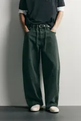 Pantalón barrel fit de mezclilla color verde militar, con efecto lavado, cinco bolsillos, cierre frontal con cremallera y botón, y detalle de pinzas en las rodillas.