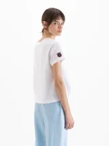Remera blanca con estampado frontal de flor pintada al estilo acuarela, de manga corta y cuello redondo.