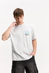 Remera oversize de algodón color gris oscuro, con diseño gráfico estampado en la espalda en tonos celestes y salmón, acompañado del texto "Mistral 1976".