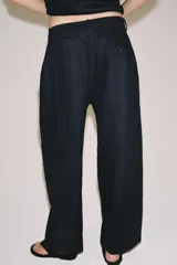 Pantalón de tiro medio confeccionado en 100% lino, color blanco, de corte amplio y recto. Cuenta con cintura elástica posterior, trabillas, pinzas en el delantero, bolsillos laterales y cierre frontal con cremallera y botón oculto.