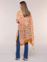 Kimono de gasa ligera con diseño estampado en tonos naranja y blanco, corte amplio y abierto al frente, mangas cortas integradas y detalle de borlas en el ruedo asimétrico.
