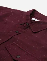 Camisa de franela verde oscuro jaspeada, de manga larga, con cuello clásico, cierre frontal con botones, bolsillo de parche en el pecho y puños abotonados.