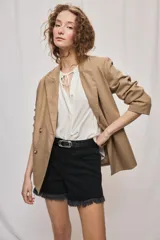 Blazer de silueta amplia y largo por debajo de la cadera, color café, confeccionado en tela suave y liviana. Presenta cuello con solapas, cierre cruzado con botones y bolsillos laterales con tapa.