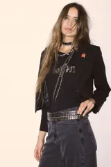 Saco negro de corte entallado con solapas clásicas, cierre frontal y hombreras estructuradas. Presenta un diseño minimalista y elegante con forro interior.