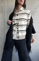 Cardigan de punto con diseño de rayas horizontales en tonos crema, beige y negro, con cuello redondo y cierre frontal de botones negros.