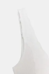Top de punto canalé en color beige, con escote en pico adornado con una delicada aplicación de encaje blanco y tirantes anchos.