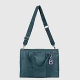 Bolso tipo tote de la marca Bubba, color verde petróleo, con doble asa de mano y correa larga ajustable y extraíble con logo grabado. Incluye cierre principal, bolsillo interior y un dije colgante con la letra B en color rosado.