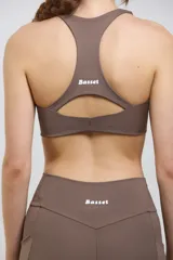 Top deportivo de compresión media con escote redondo, diseño al cuerpo y espalda abierta. Cuenta con elástico interno en la cintura para mayor sujeción.