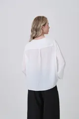 Blusa de poliéster color verde oliva, con cuello redondo, cierre frontal parcial con botones y mangas tres cuartos.