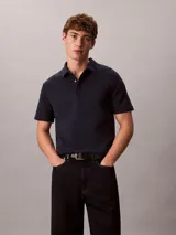 Chomba de manga corta Calvin Klein confeccionada en algodón interlock, con cuello clásico y cierre frontal de botones. Presenta un diseño liso en color azul marino con el logo de la marca sutilmente bordado en el pecho.