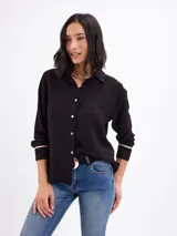 Camisa de nylon y algodón color negro con cuello camisero, cierre frontal de botones y detalles de vivos en los puños.
