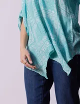 Camisa celeste con estampado de cachemir en blanco, cuello a la base, escote en V y abertura central con botones. Terminación de ruedo asimétrico. Manga 3/4 de largo regulable con presilla y botón.