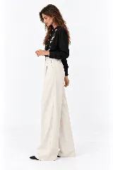Pantalón de lino natural de tiro alto, corte wide leg y pinzas en la parte delantera. Cuenta con un pequeño bolsillo lateral con tapa y botón decorativo en la pretina.