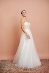 Vestido largo de microtul blanco con brillo y apliques de flores, con breteles finos y falda con vuelo. Ideal para quinceañeras.