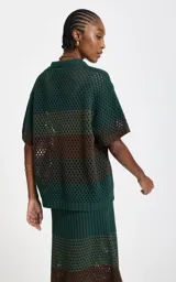 Camisa de punto calado con rayas horizontales en verde oscuro y marrón, cuello polo en V, mangas cortas holgadas y ribetes acanalados en los puños y el bajo.
