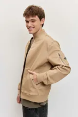 Campera bomber de gabardina color tostado, con cierre frontal y bolsillos laterales, puños y cintura elastizados de rib.