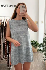 Vestido tejido de punto sin mangas, corte recto y holgado, con cuello redondo. El tejido es jaspeado en tonos grises, azules y amarillos claros, con brillo sutil de lurex.