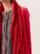 Bufanda gruesa de lana, color rosa claro con motas rosadas y blancas, tejida con punto grueso y textura afelpada.