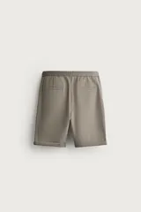 Bermuda regular fit de tejido elástico color blanco, con cintura elástica ajustable mediante cordón, bolsillos delanteros y bolsillos traseros de vivo.
