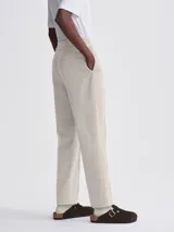 Pantalón de vestir color beige, de corte recto, con pinzas delanteras y cintura elástica lateral.