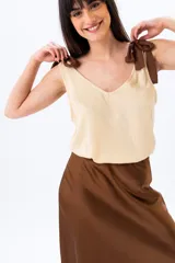 Musculosa beige con breteles anchos que se atan en los hombros.