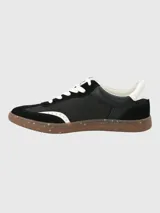Zapatillas urbanas de diseño deportivo, color negro con detalles en blanco y suela de goma color caramelo con efecto moteado.