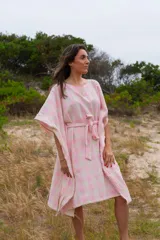 Túnica de corte holgado con estampado a cuadros en tonos rosa y crudo, con cuello redondo y mangas cortas amplias. Incluye cinturón de la misma tela para ajustar a la cintura.