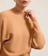 Blusa de punto acanalado color tostado, con cuello alto, mangas largas y puños ajustados. Confeccionada en viscosa, poliéster y poliamida.