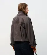 Campera de gamuza sintética color tostado con botones dorados grabados, cuello camisero, bolsillos frontales aplicados y mangas largas con puños abotonados.