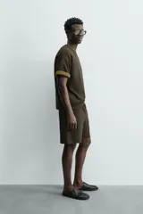 Bermuda de hombre color verde oscuro, de corte relajado y tiro medio. Confeccionada en tejido texturado, presenta cintura elástica con cordón de ajuste interno y bolsillos laterales y trasero de vivo.