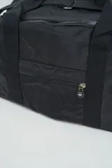 Bolso de viaje color negro con múltiples compartimentos con cierre, doble asa de mano y correa ajustable para el hombro.